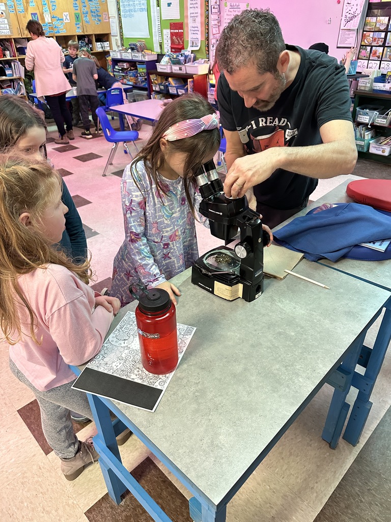 2nd graders learning how to look through a microscope